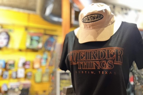 Mannequin wearing a black shirt that says 'Weirder Things' and a 'Keep Austin Weird' hat